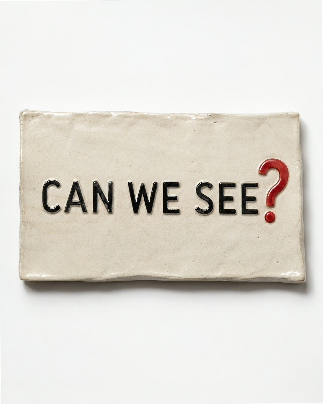 A ceramic plaque reading can we see with a glossy red question mark