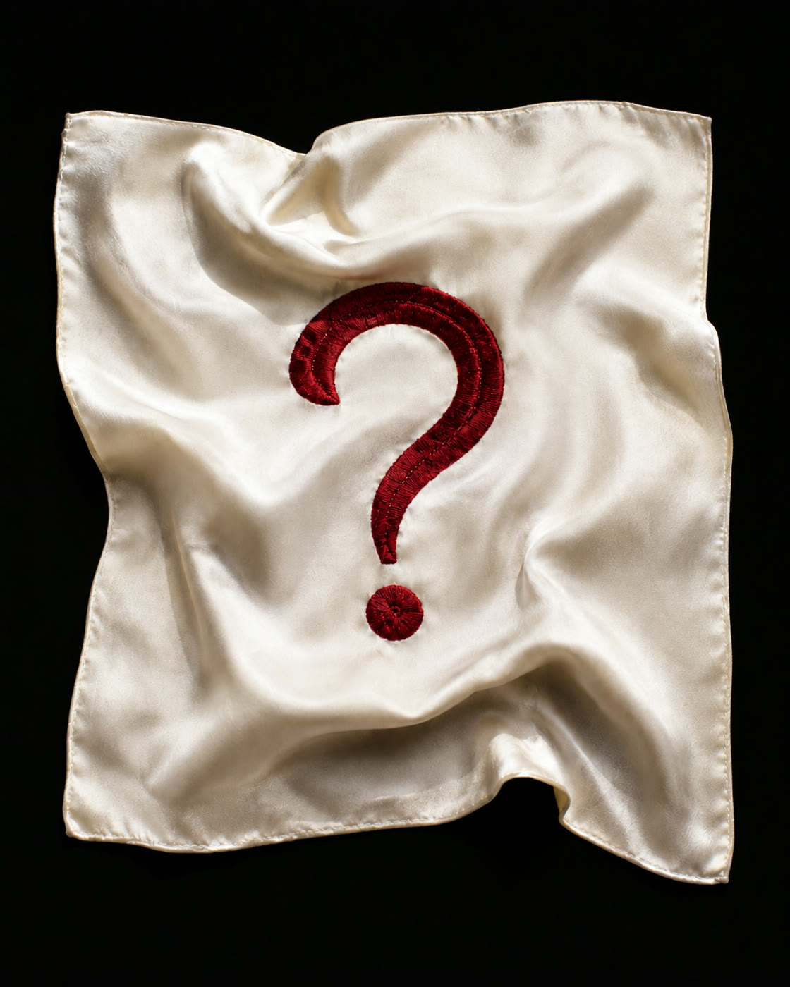 A red question mark on draped white silk